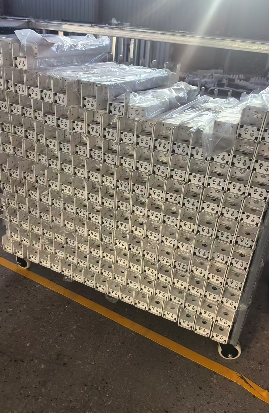 Wrapped white standing desk column components grouped on a workshop trolley